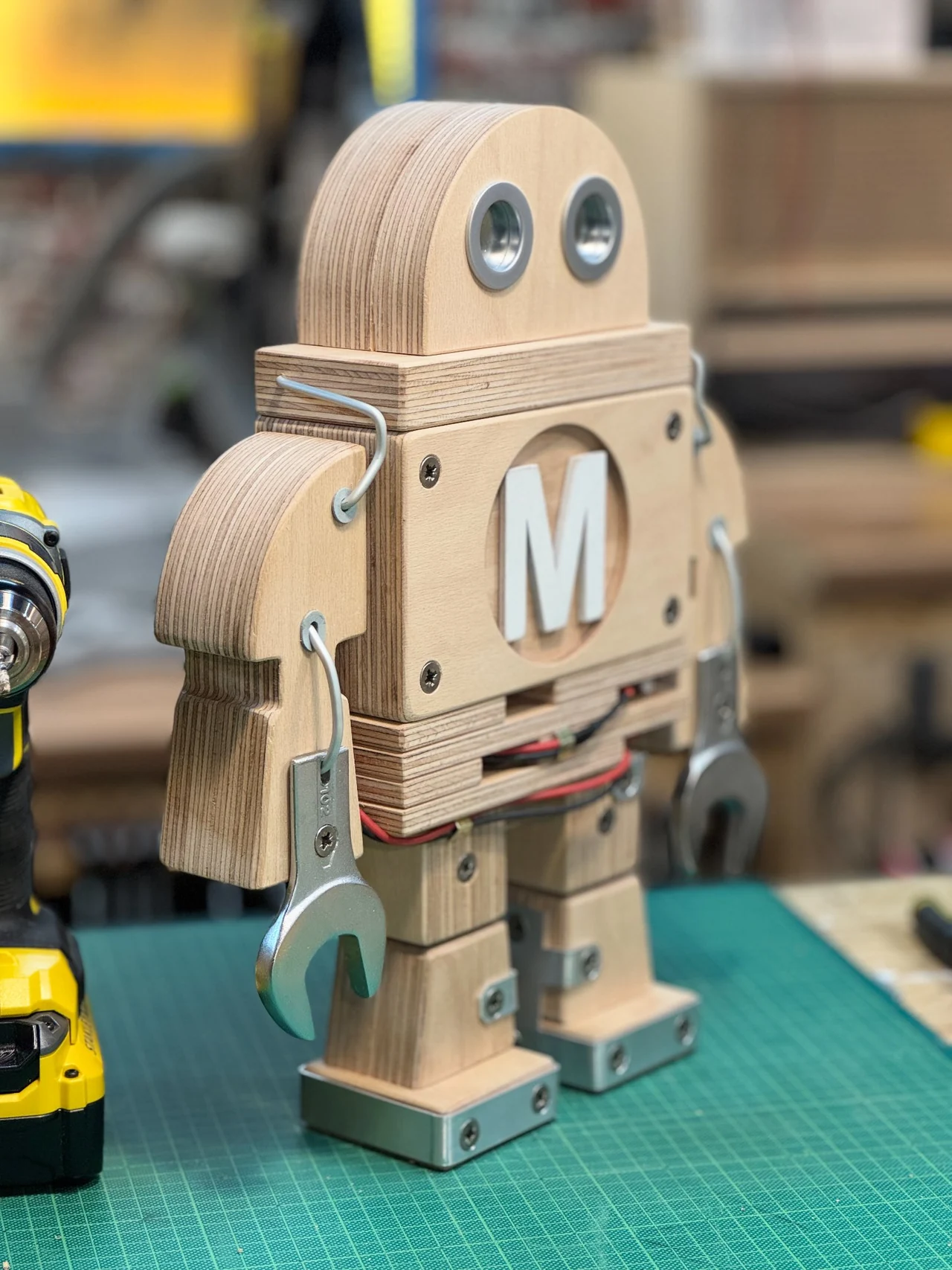 Seitliche Detailansicht der Makey-Figur mit sichtbaren Holzschichten, Draht und einer Schraubenschlüssel-Hand