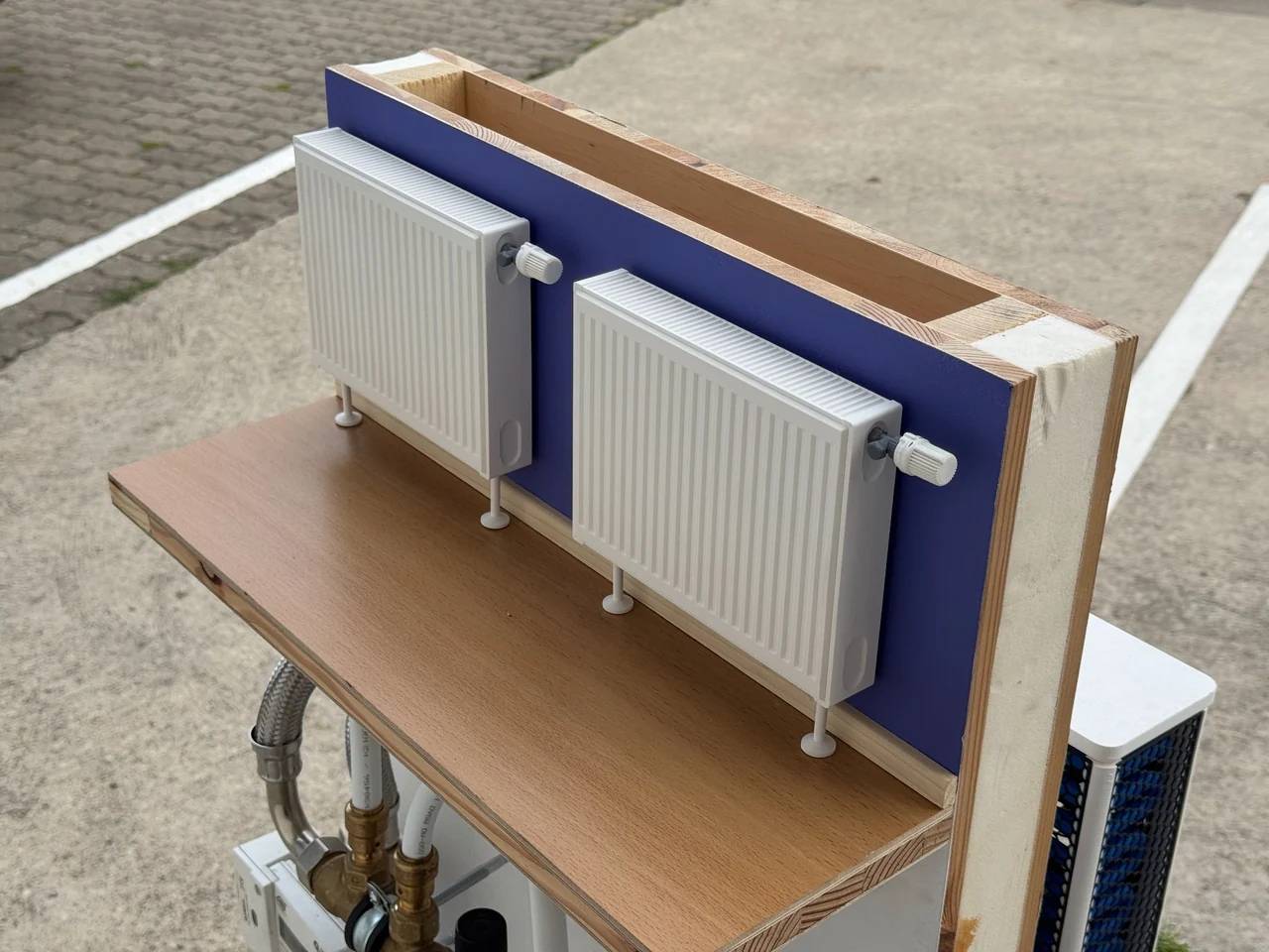 Zwei 3D-gedruckte Heizkörper mit nachgebildeten Thermostatventilen auf der Innenseite der Modellwand
